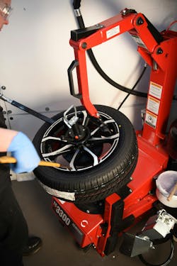 Tire being mounted. Notice the yellow tire dot aligned to the valve stem, matching the tire&rsquo;s light spot to the wheel&rsquo;s heavy spot.